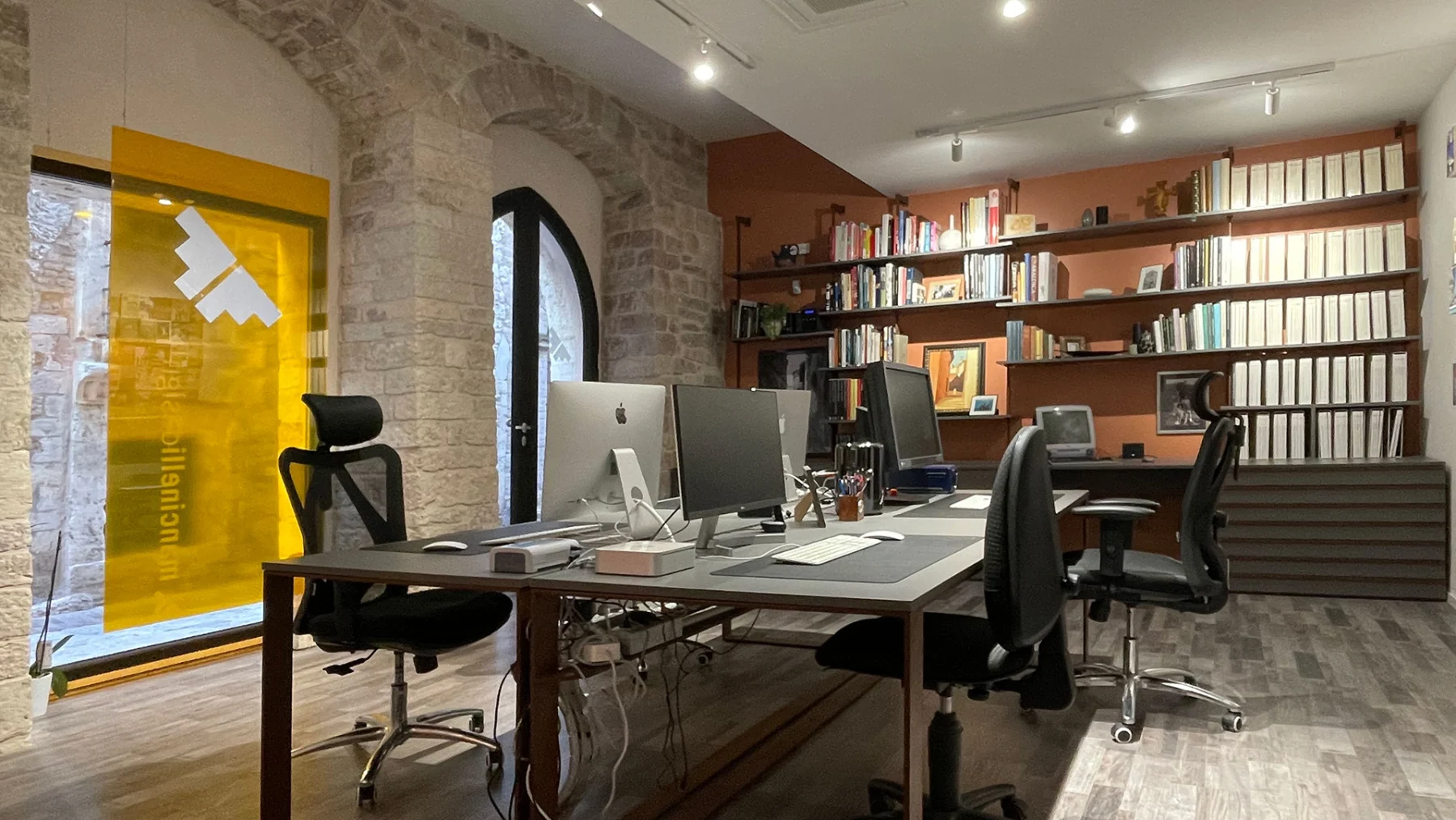 Postazione di lavoro dello studio, con pareti in pietra e libreria